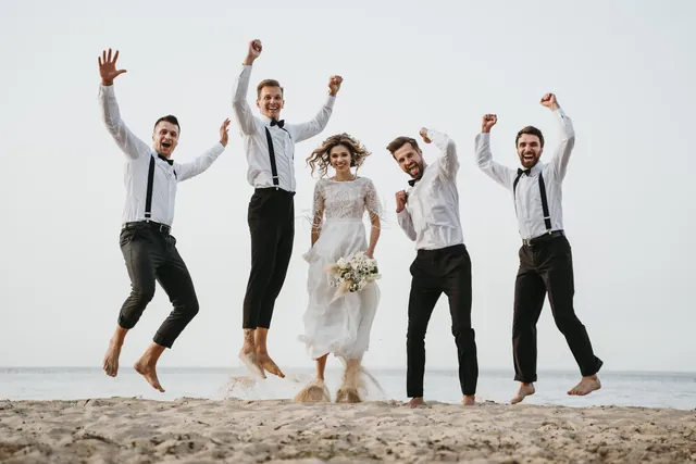 The wedding party jumping together on the beach